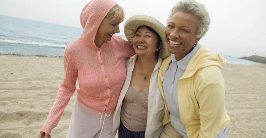 Three woman walking on a beach, laughing